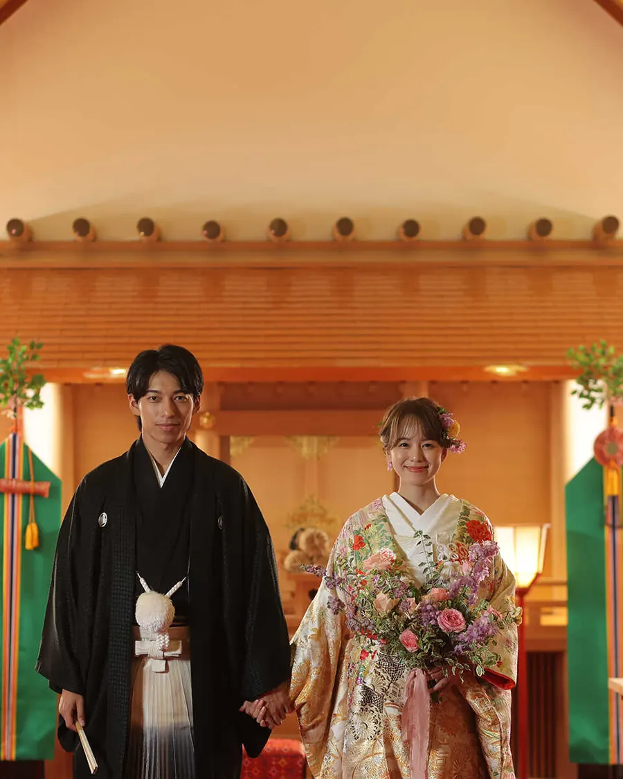 館内神殿に立つ紋付袴と色打掛の新郎新婦